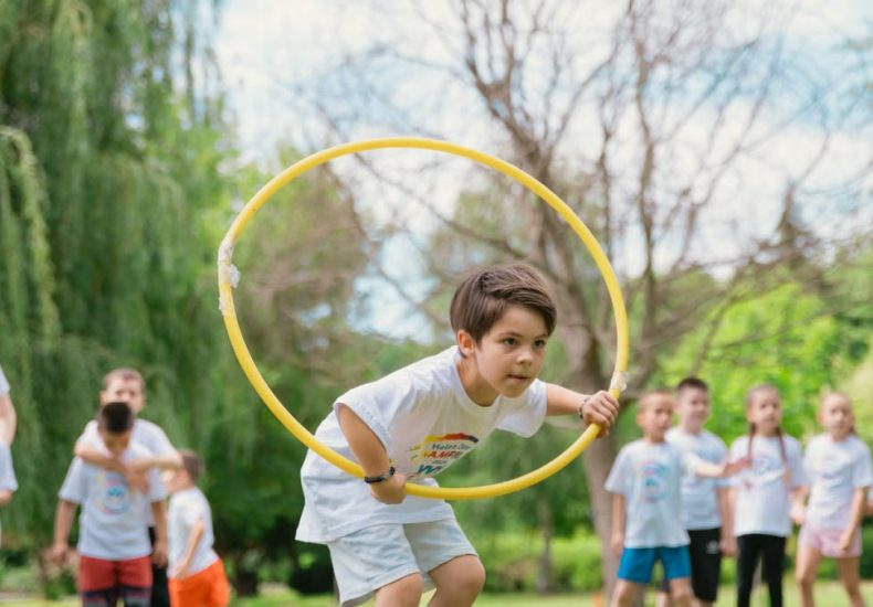 Kids enjoying a summer day playing with hula hoops in a park, showcasing friendship and fun.